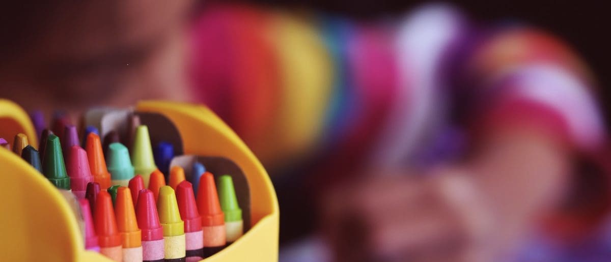 selective focal photo of crayons in yellow box
